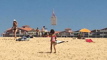 Une plage de sable avec des parasols et un poste de surveillance pour les sauveteurs.