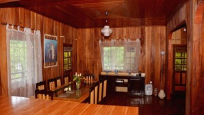 A wooden interior with a dining table, chairs, and a kitchen area.