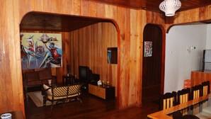 A wooden interior with a sofa, TV, and dining area.
