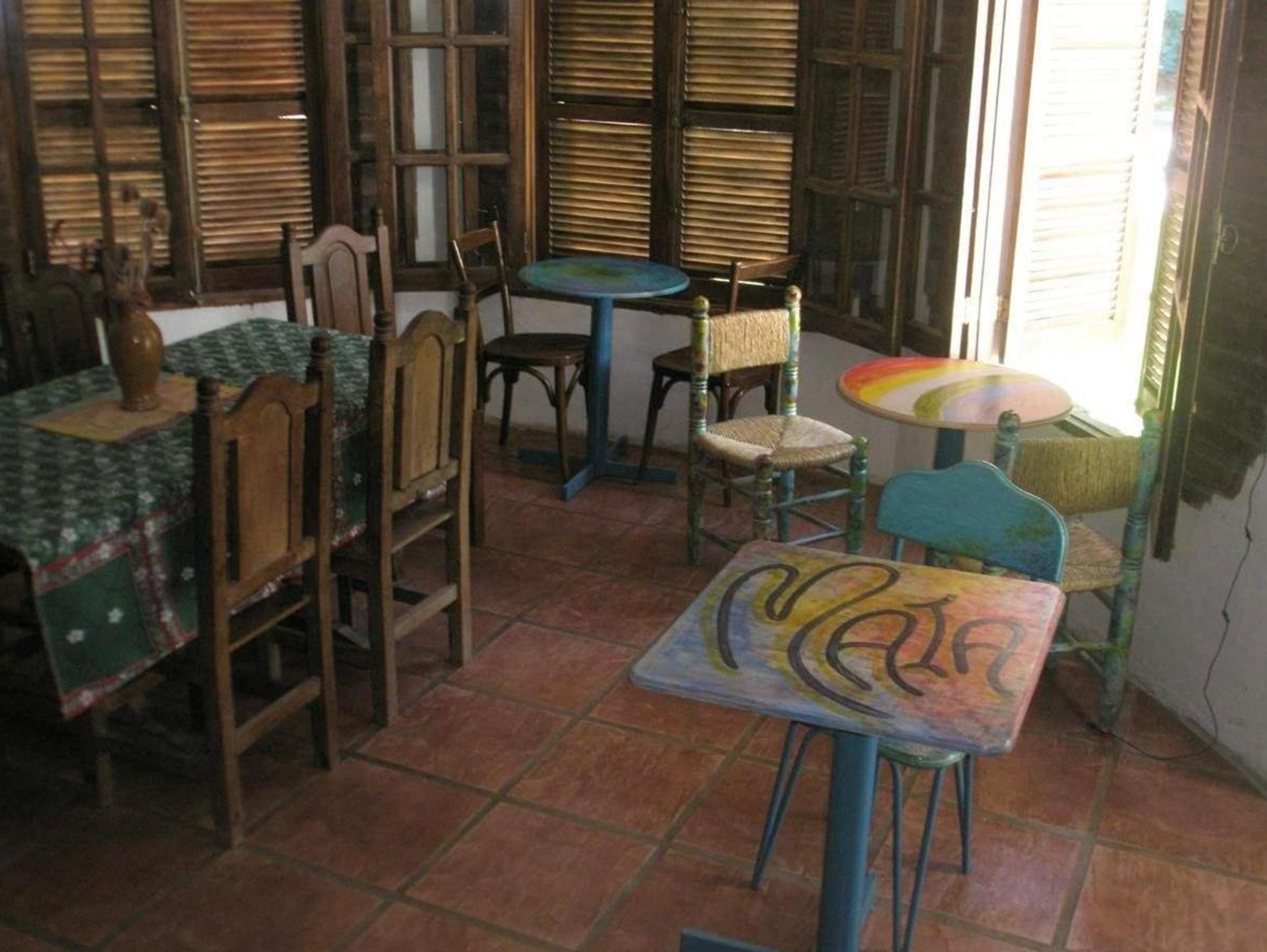 Una habitación con muebles de madera, incluyendo sillas y una mesa, y suelo de baldosas.