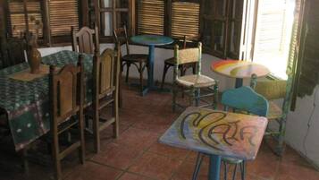 Una habitación con muebles de madera, incluyendo sillas y una mesa, y suelo de baldosas.
