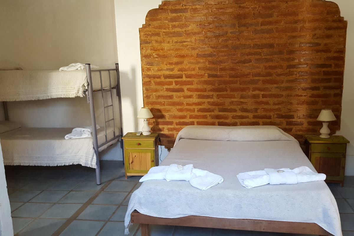 Ein Zimmer mit Etagenbett, einem Einzelbett und zwei Nachttischen mit Lampen.