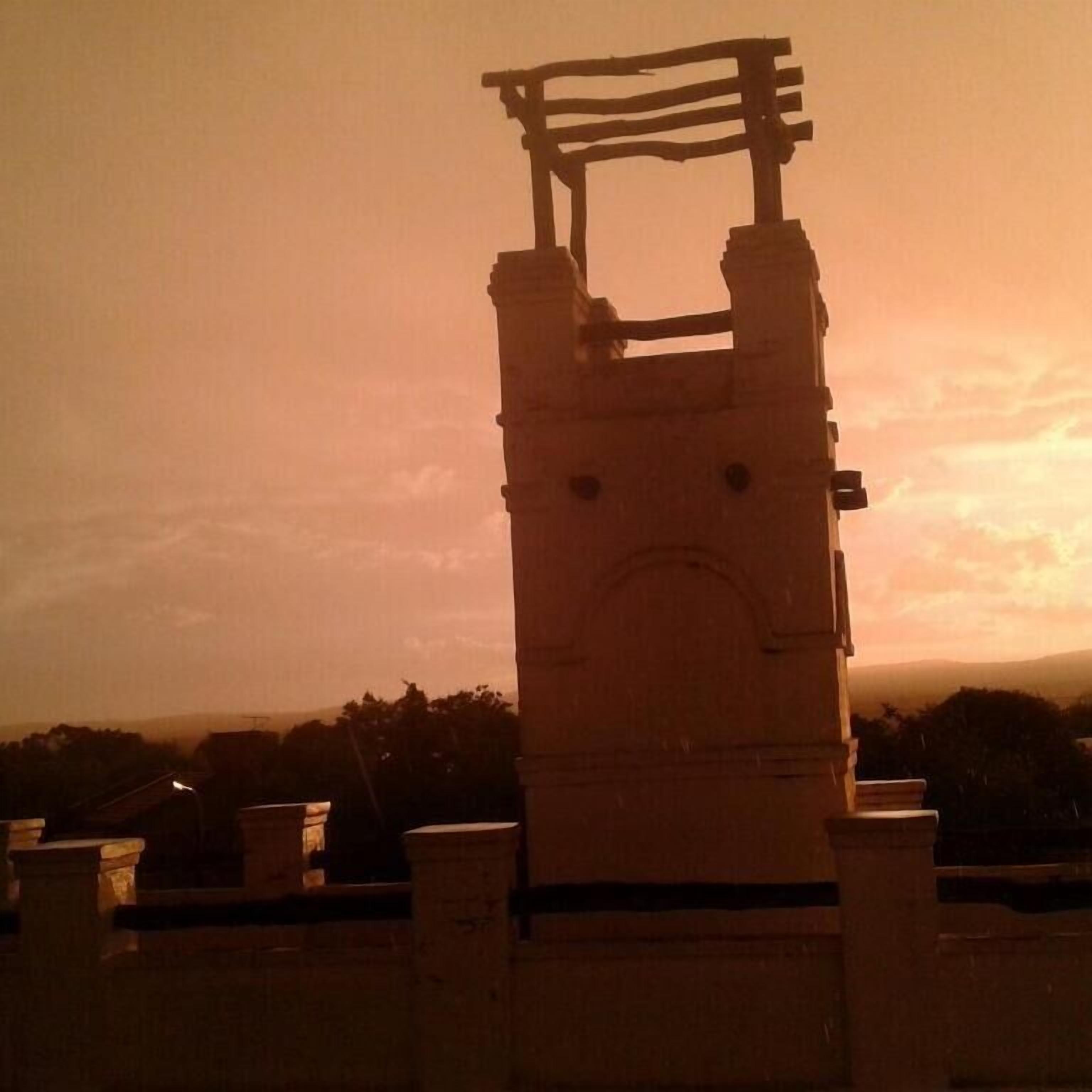 Una estructura de piedra con una puerta, posiblemente un monumento histórico, al atardecer.