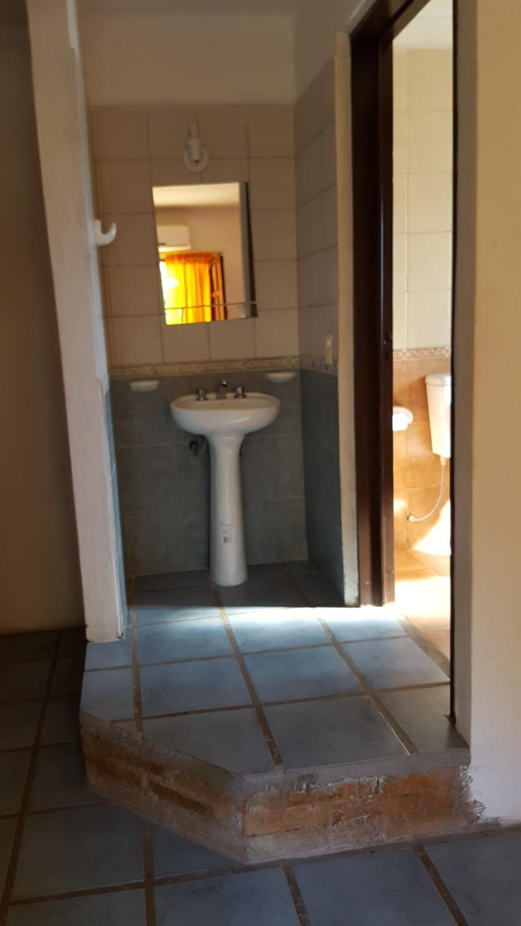 A bathroom with a white sink, tiled walls, and a visible shower area.