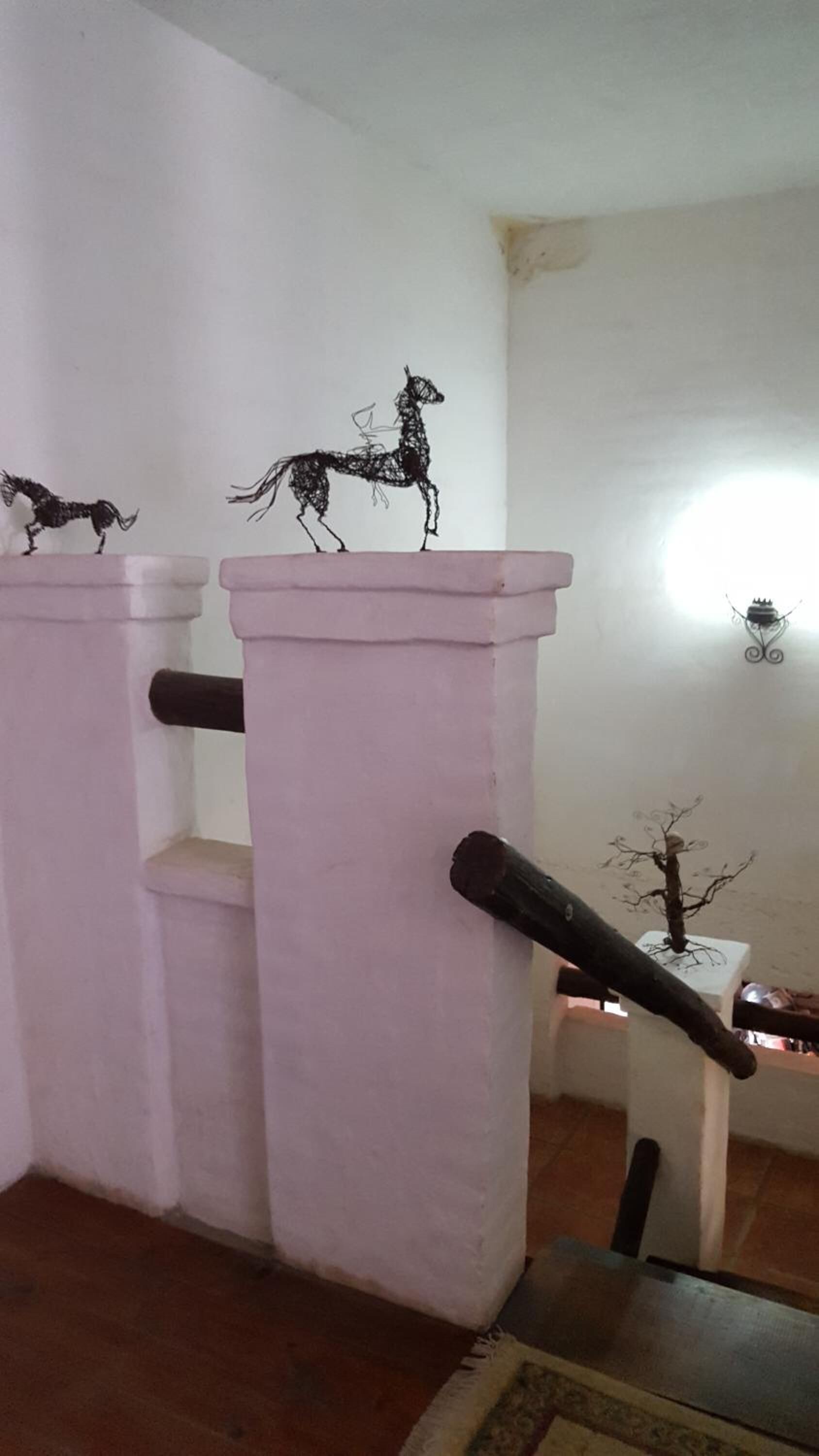 A room with a pink column and a decorative metal sculpture of a horse.