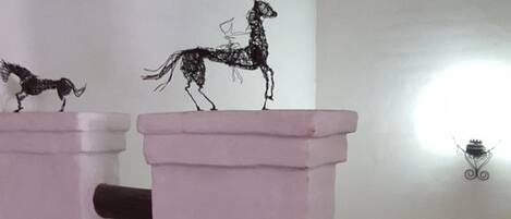 A room with a pink column and a decorative metal sculpture of a horse.