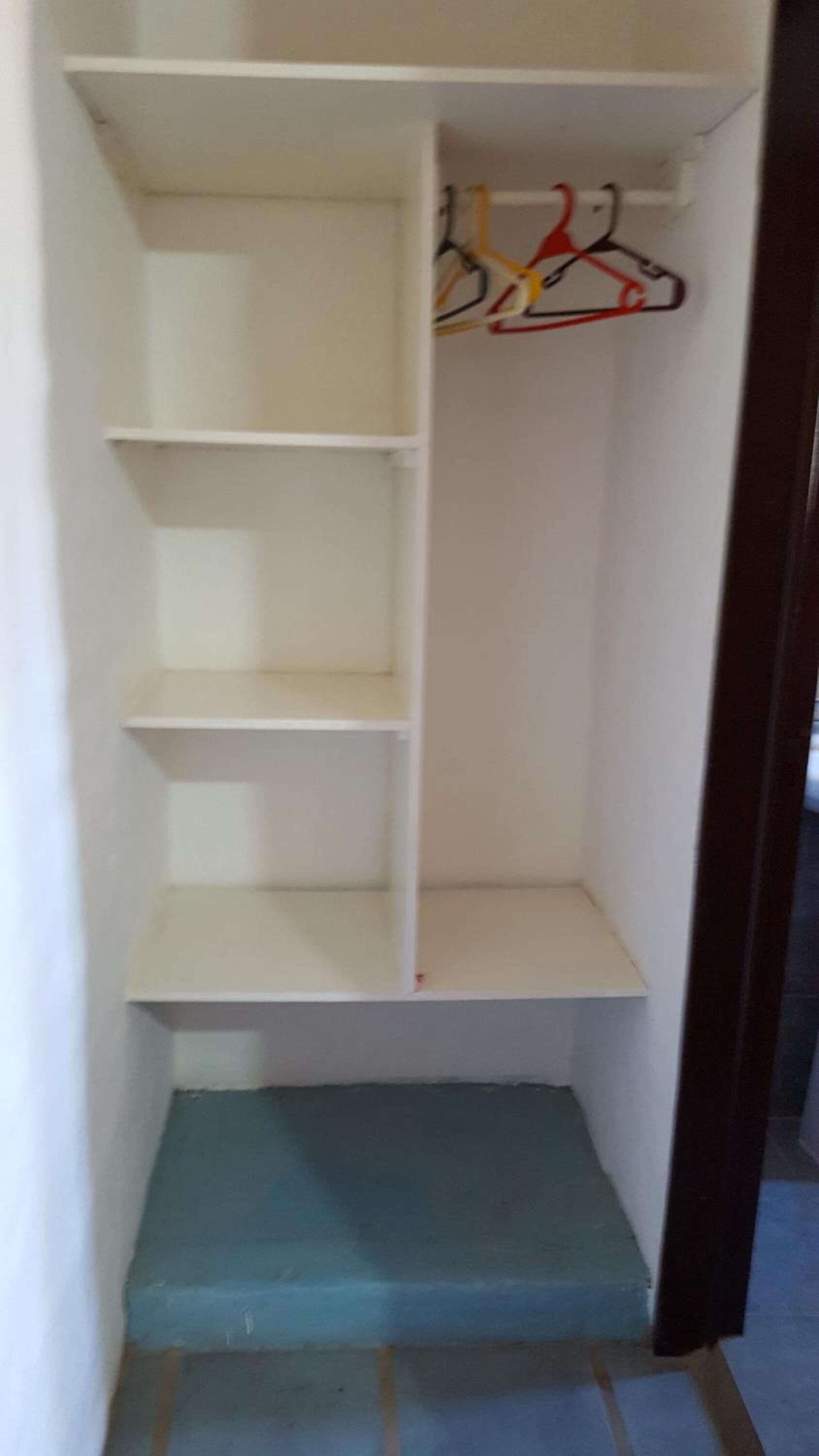 Um armário com várias prateleiras e uma barra para pendurar roupas.