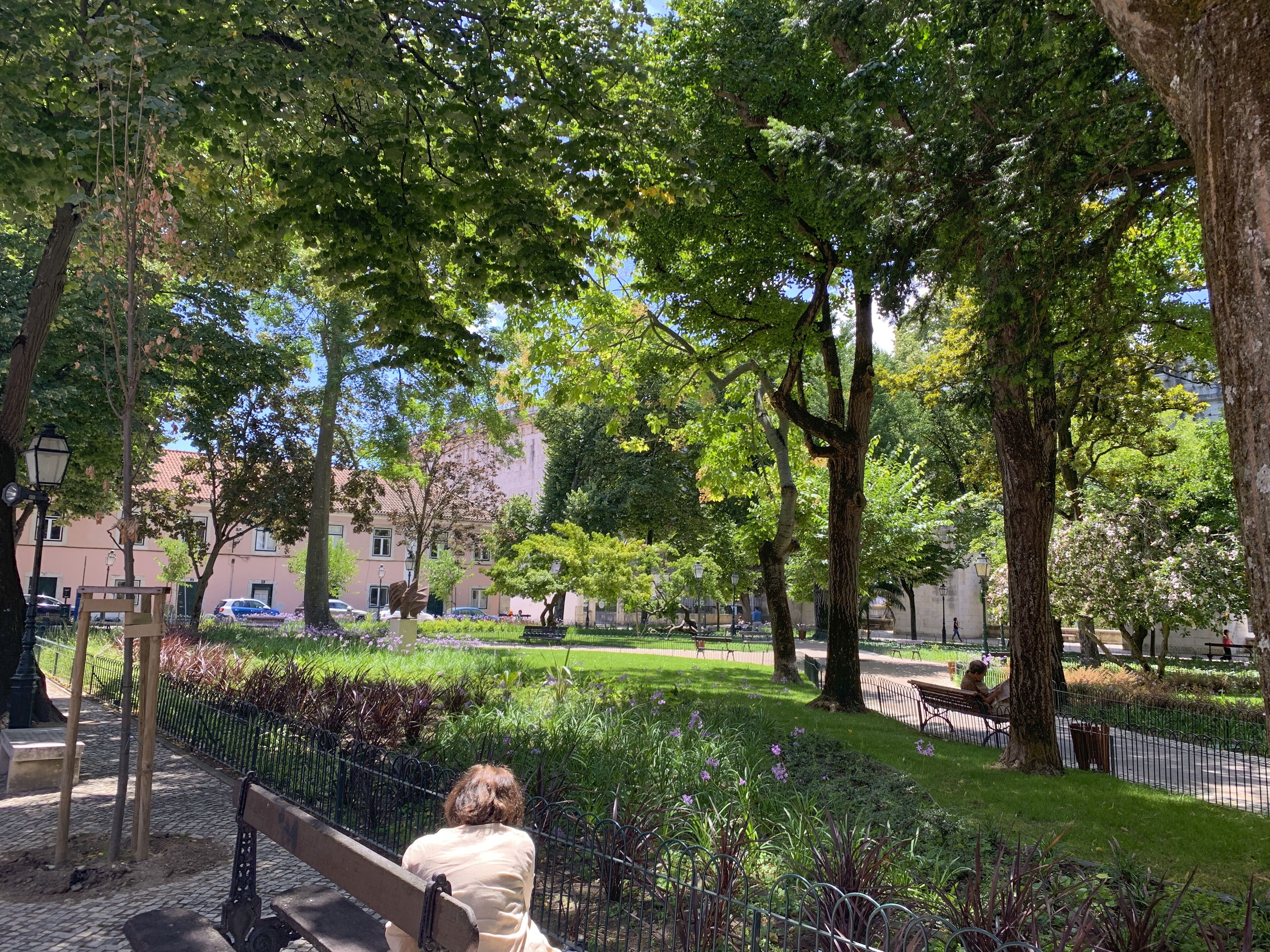 Un parc avec des bancs, des arbres et un chemin piétonnier dallé.