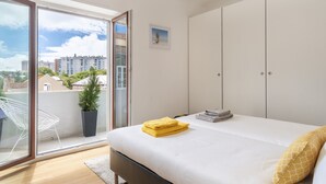 A bedroom with a bed, a window, and a view of buildings.