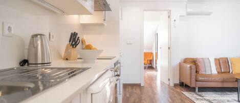 A modern kitchen with a stainless steel range hood, a kettle, and a bowl of fruit on the counter.