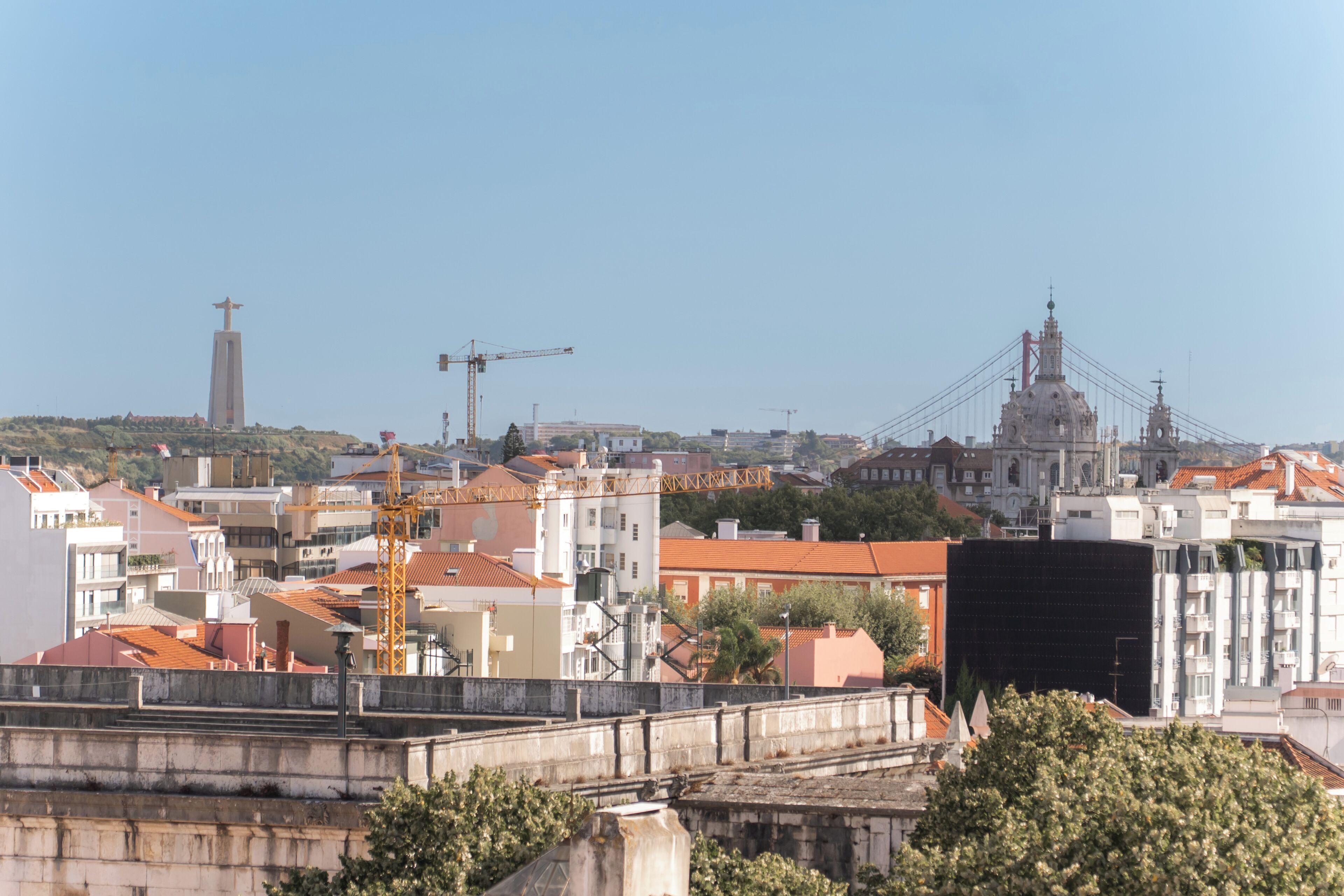 Eine Stadtansicht mit einer markanten Brücke, einer Kirche und einer Statue auf einem Hügel.