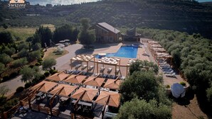 Een resort met een zwembad, terras en een berg op de achtergrond.
