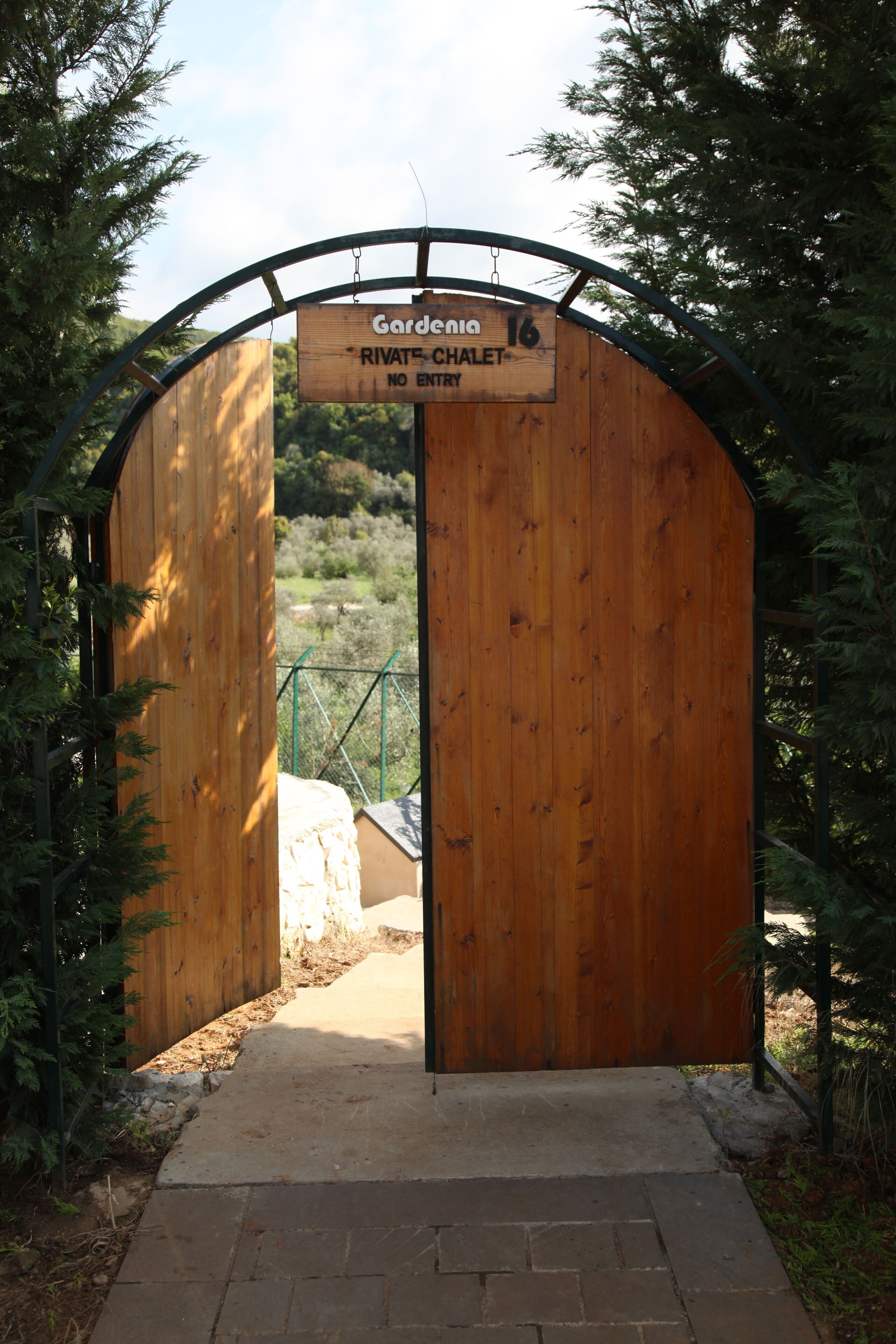 A wooden archway with a sign reading "Gardenia 16 RIVATE CHATEAU NO ENTRY".