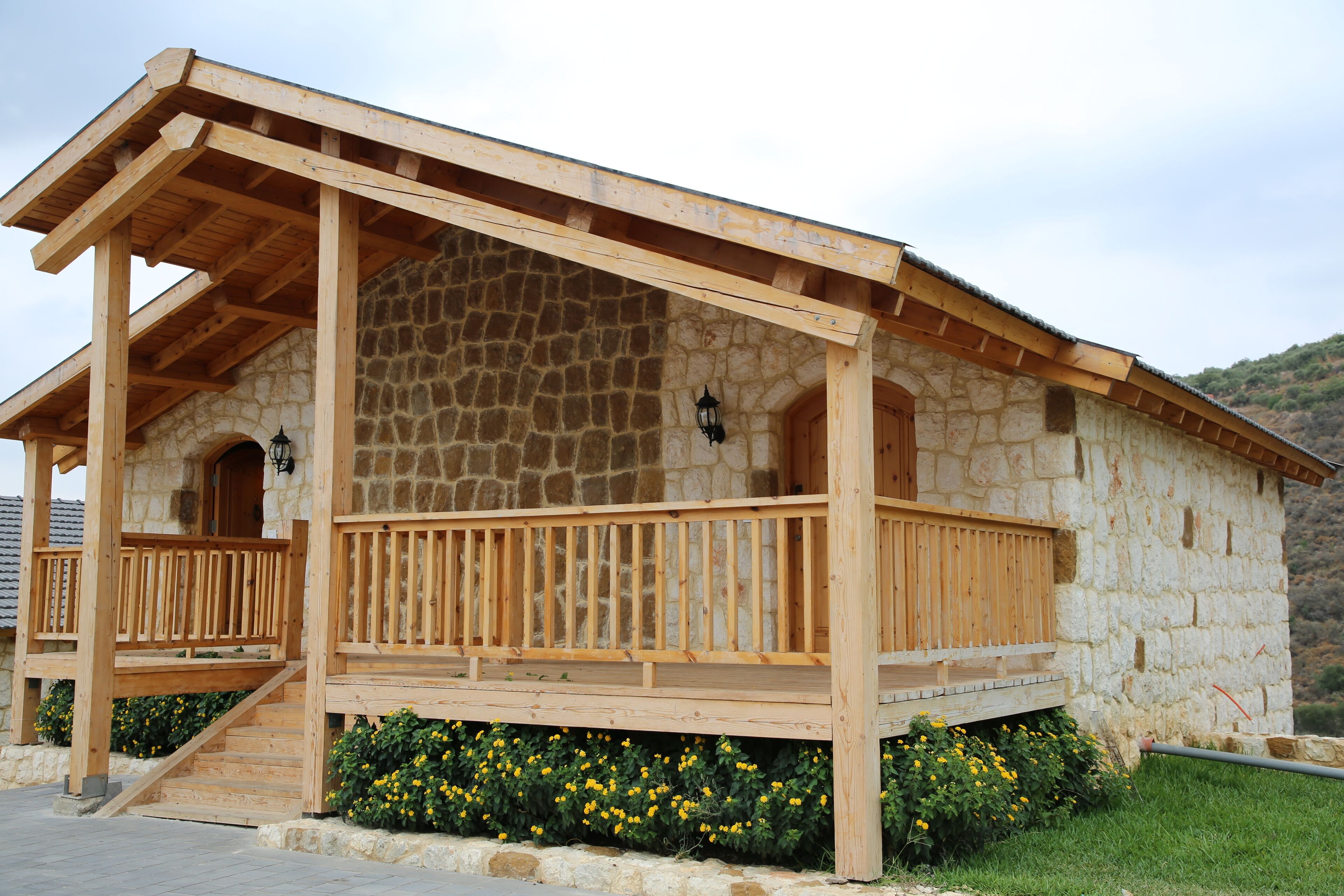 Un bâtiment en pierre doté d’un porche en bois et d’un escalier menant à une porte.