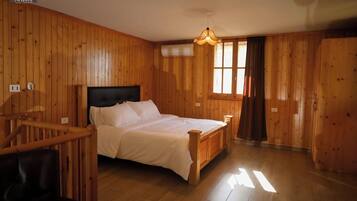 A wooden-paneled room with a bed, a window, and a staircase.