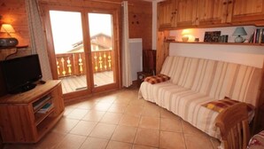 Un salon chaleureux avec un meuble TV en bois, un canapé et un balcon offrant une belle vue.