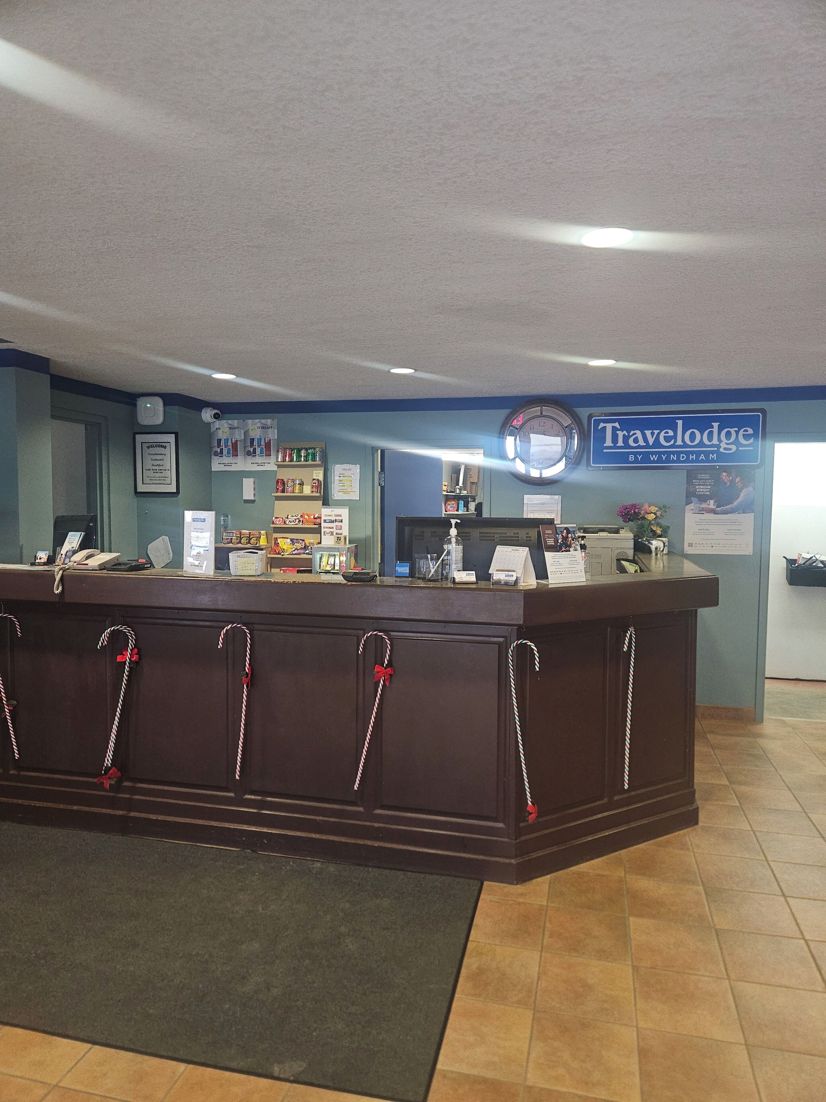 A reception desk with a clock, a welcome sign, and a Travelodge sign.