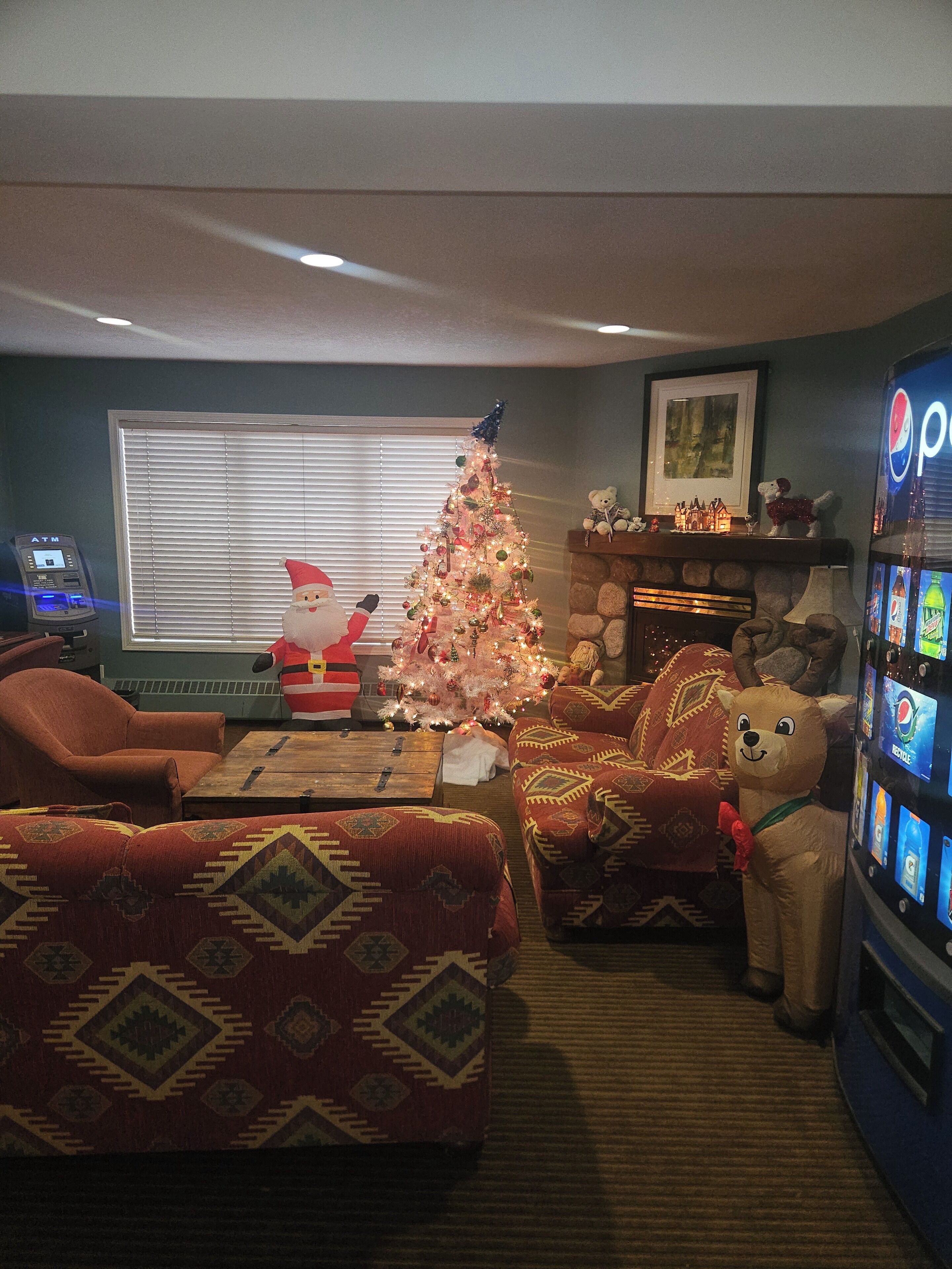 Ein Wohnzimmer mit Weihnachtsbaum, Kamin, Sofa, Couchtisch und einer Verkaufsmaschine.
