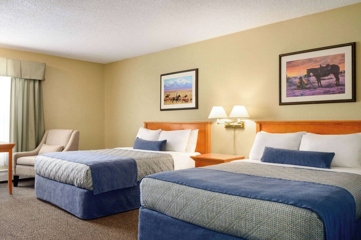 Habitació d'hotel amb dos llits, una cadira i dues làmpades penjades a la paret.