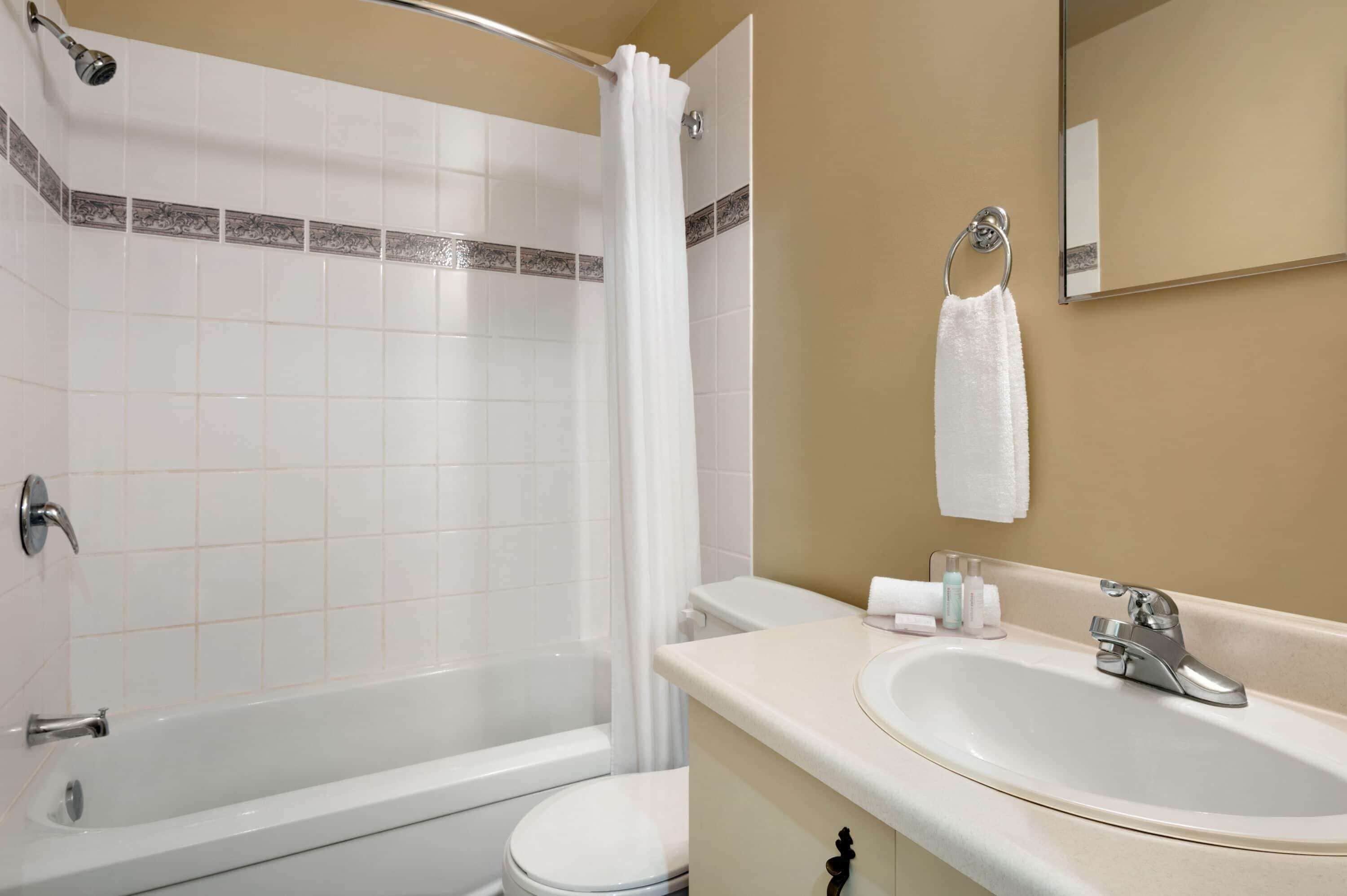 A bathroom with a bathtub, toilet, sink, and a mirror.