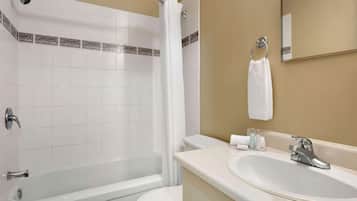 A bathroom with a bathtub, toilet, sink, and a mirror.