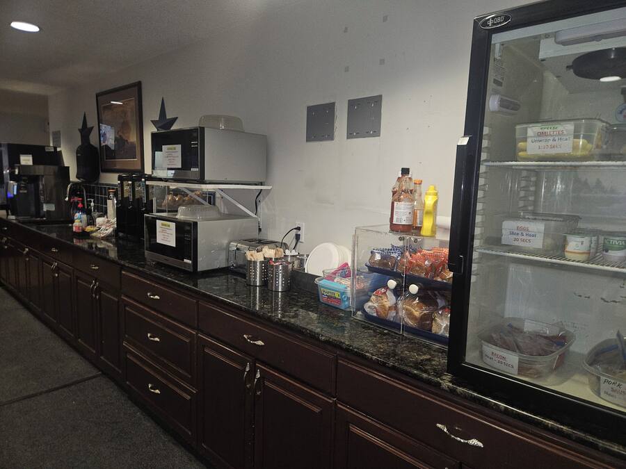 Een kitchenette met een magnetron, koffieapparaat en diverse etenswaren op het aanrecht.