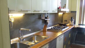 A modern kitchen with stainless steel appliances, a wooden countertop, and a built-in sink.