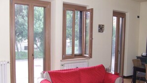 A room with a red sofa, a radiator, and a window with an open shutter.