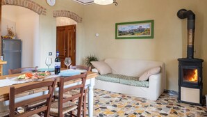 A cozy living room with a dining area, a fireplace, and a cityscape painting on the wall. - Casa Bruna - Cipresseta del Chianti (Castellina in Chianti, Siena)