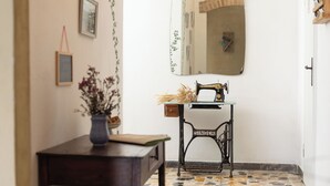 A hallway with a tiled floor, a sewing machine on a small table, and framed pictures on the wall. - Casa Bruna - Cipresseta del Chianti (Castellina in Chianti, Siena)
