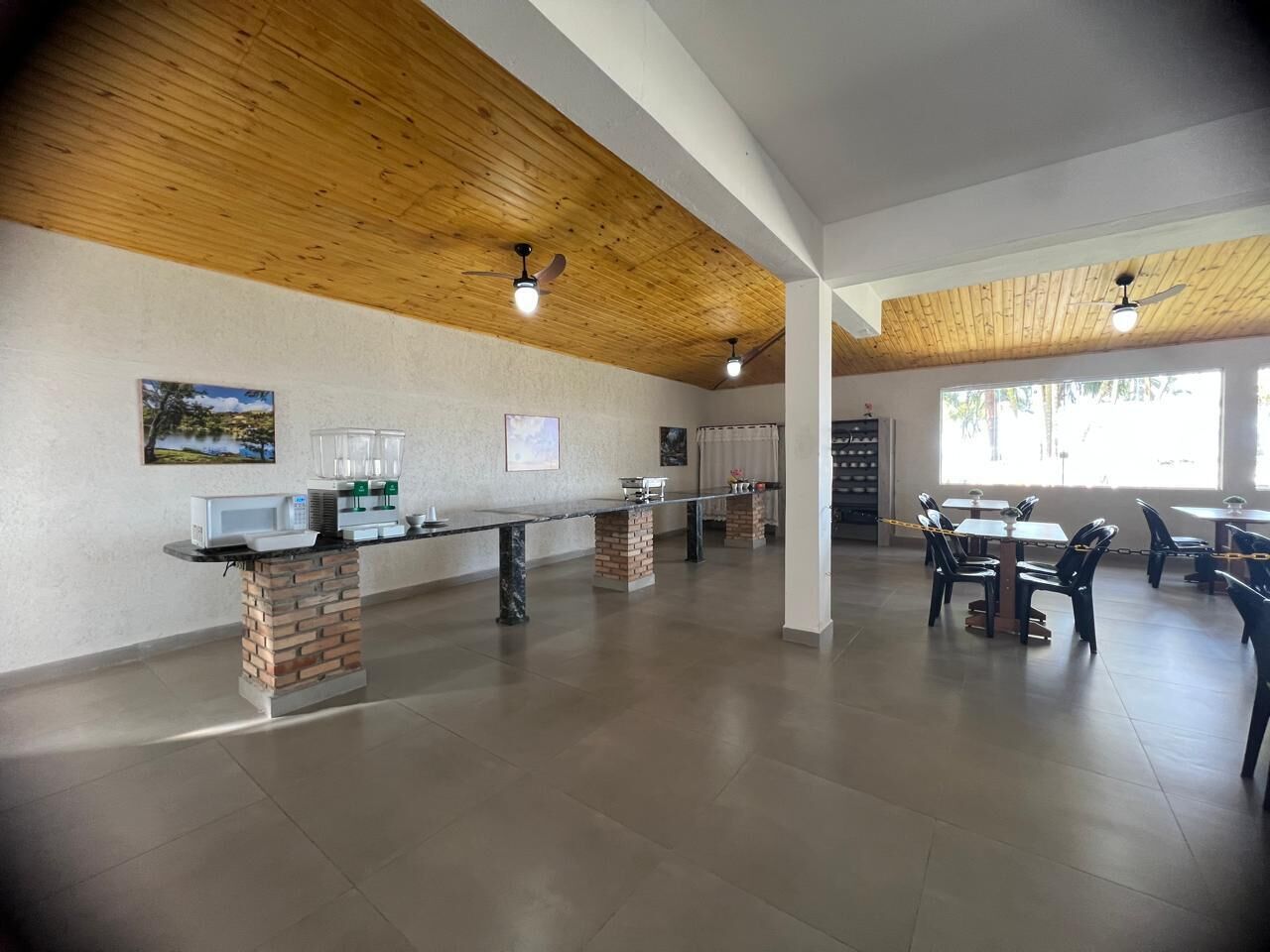A spacious indoor area with a long counter, multiple tables, and chairs.