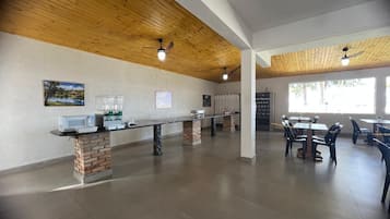 Un espacio interior amplio con una barra larga, varias mesas y sillas.