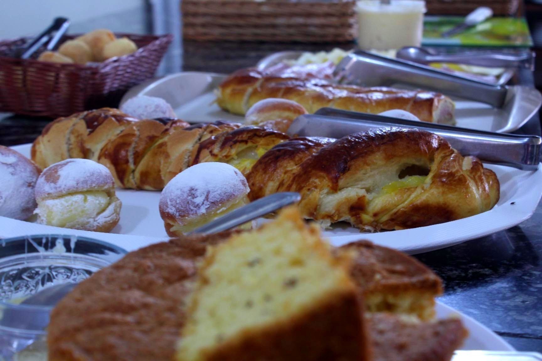 Une variété de viennoiseries et de desserts présentés sur une assiette, notamment un croissant et une pâtisserie recouverte d’un glaçage en poudre.