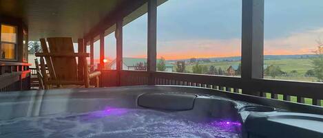 Un jacuzzi con vista al atardecer y una terraza de madera.
