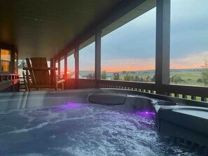 Un bain à remous avec vue sur le coucher de soleil et une terrasse en bois.