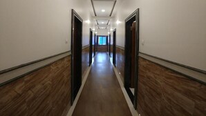 A long, narrow hallway with wooden flooring and white walls. - Hotel Jagadguru (Mawal)