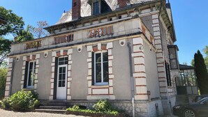 Ein historisches Gebäude mit einer symmetrischen Fassade, großen Fenstern und einem markanten Schornstein.