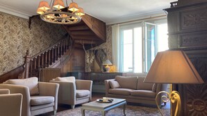 Ein geräumiges Wohnzimmer mit einer imposanten Treppe, stilvollem Mobiliar und einem Kronleuchter.