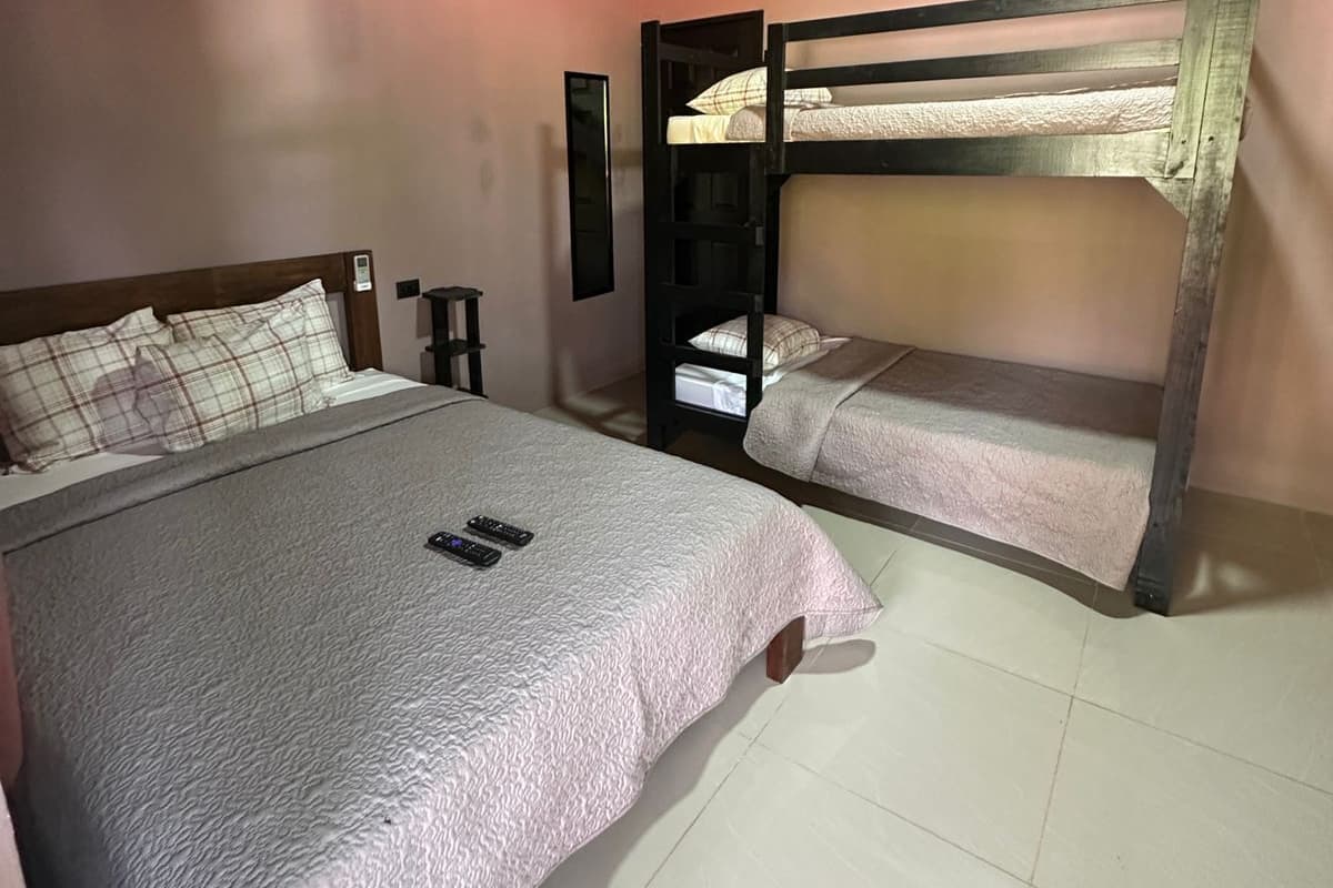 A bedroom with two bunk beds, a large bed, and a bedside table with a lamp.