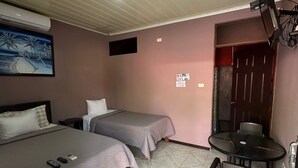 A hotel room with two beds, a TV mounted on the wall, a small table with chairs, and a tiled floor. - Cabinas Hukats Secret Jungle (Cahuita)