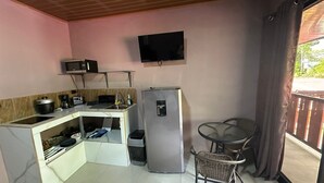 A compact kitchen with a microwave, toaster, sink, and refrigerator. There's a small dining table with a chair. - Cabinas Hukats Secret Jungle (Cahuita)