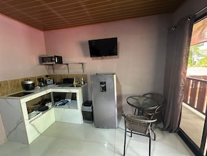 Eine kompakte Küche mit Mikrowelle, Toaster, Spüle und Kühlschrank. Es gibt einen kleinen Esstisch mit einem Stuhl.
