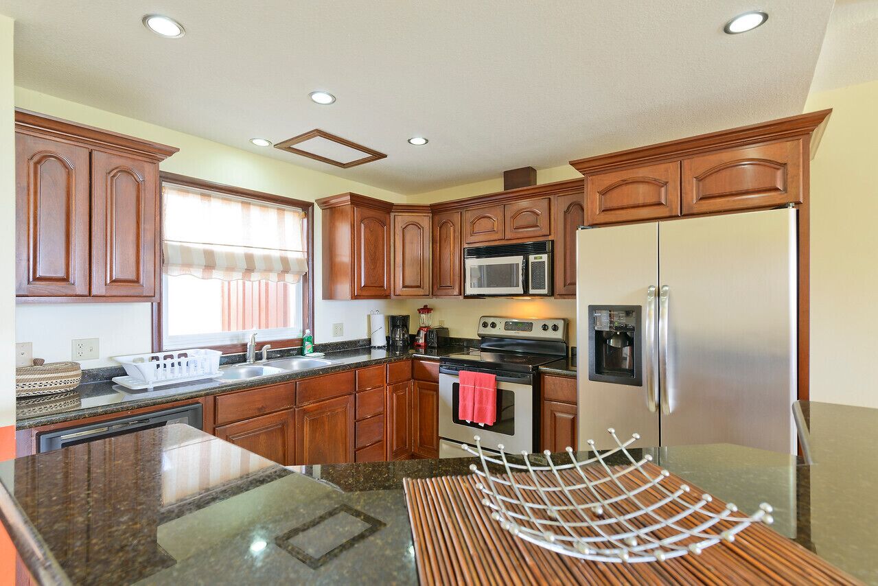 A modern kitchen with wooden cabinets, stainless steel appliances, and a granite countertop.