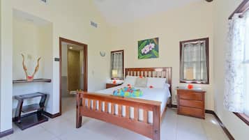 Un dormitorio con una cama de madera, mesitas de noche, un tocador, un espejo y una ventana con cortinas.