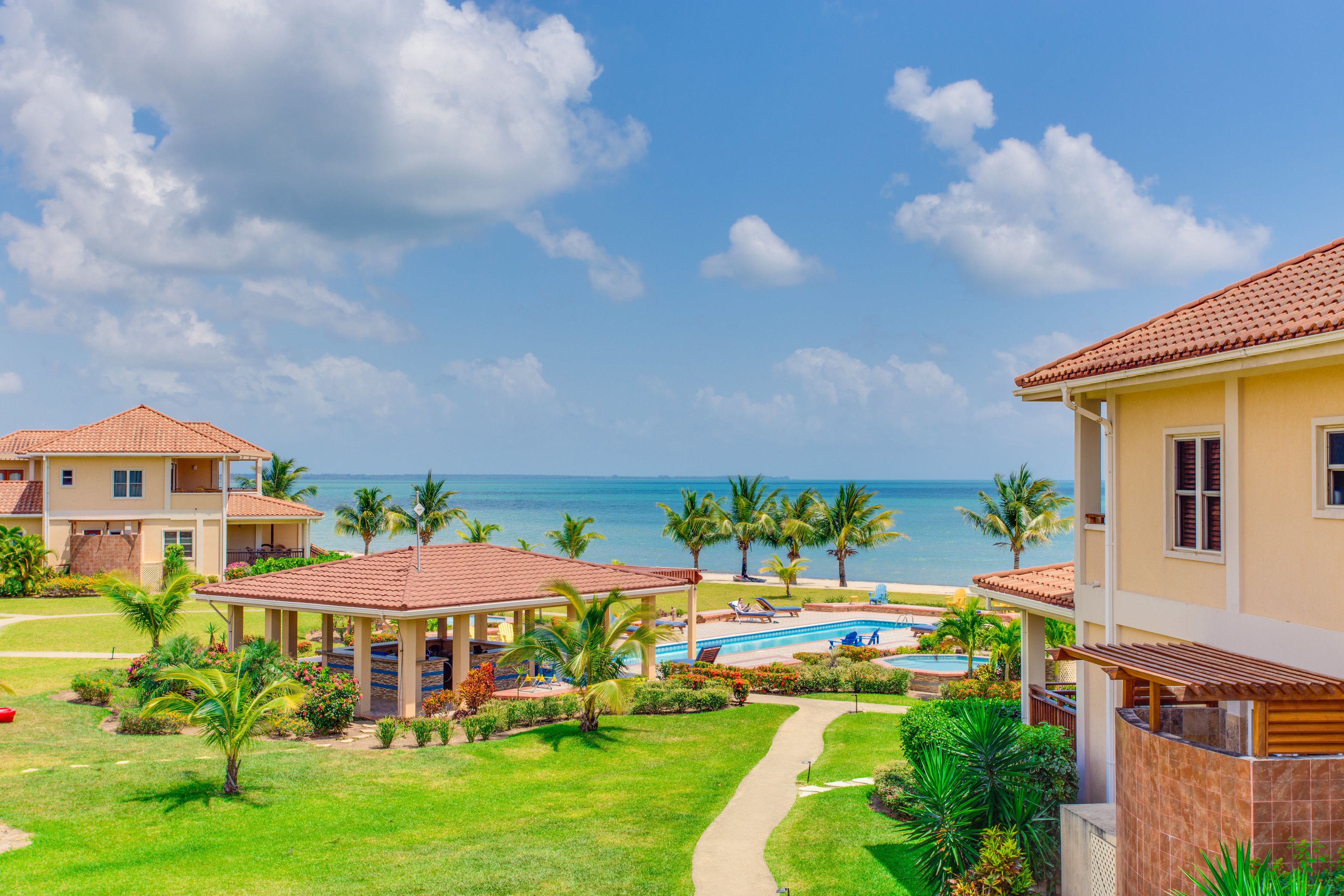 A resort with a swimming pool, palm trees, and a view of the ocean.