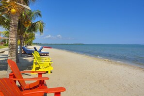 Di pantai, pasir putih, kursi berjemur, dan payung pantai