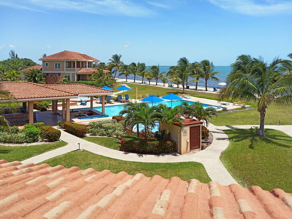 A resort with multiple swimming pools, palm trees, and a beach view.
