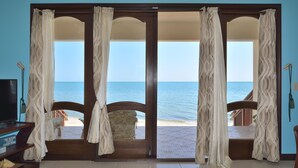 Una habitación con un amplio ventanal corredero que da a vista al mar.
