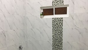 A bathroom with a toilet, shower, and a small window with a decorative screen. - villa with a private garage ,build out of shipping container,fll two rooms and two bathrooms ,dining kitchen ,plenty outdoor space for barbecue (San Miguel)