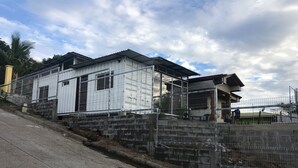 A residential building with a metal fence, concrete steps, and a paved road. - villa with a private garage ,build out of shipping container,fll two rooms and two bathrooms ,dining kitchen ,plenty outdoor space for barbecue (San Miguel)